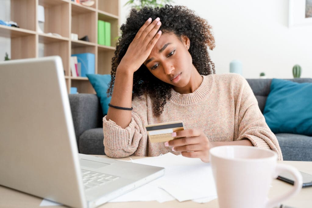 Concerned shopper sitting at desk with laptop. 