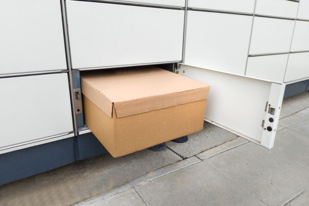 Apartment package locker with a bulky cardboard box sticking out of the compartment, showing inefficiency and limited capacity for larger deliveries.