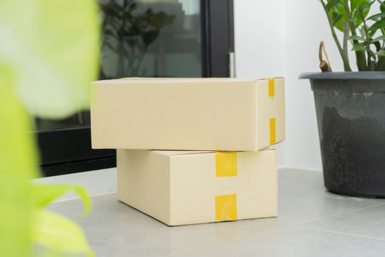 Two cardboard parcels stacked neatly on the floor near a doorway, representing efficient package management solutions for multifamily properties.