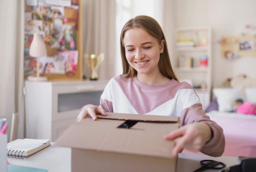 College student opening a package delivery box in off-campus housing, highlighting modern student housing package management solutions.
