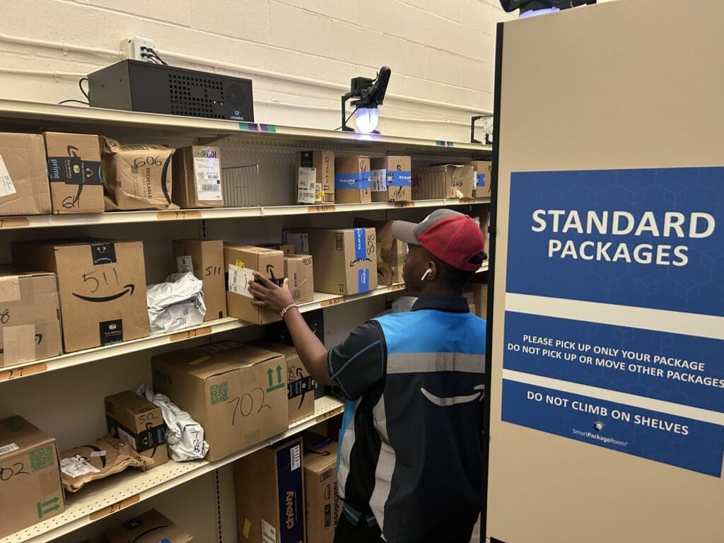Courier organizing parcels on open shelving inside a Smart Package Room, demonstrating efficient and secure package management solutions during the holiday season.