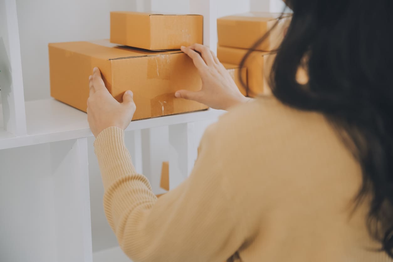 Person organizing delivery boxes on shelving, representing how technology can automate package management in multifamily buildings for greater efficiency and security.