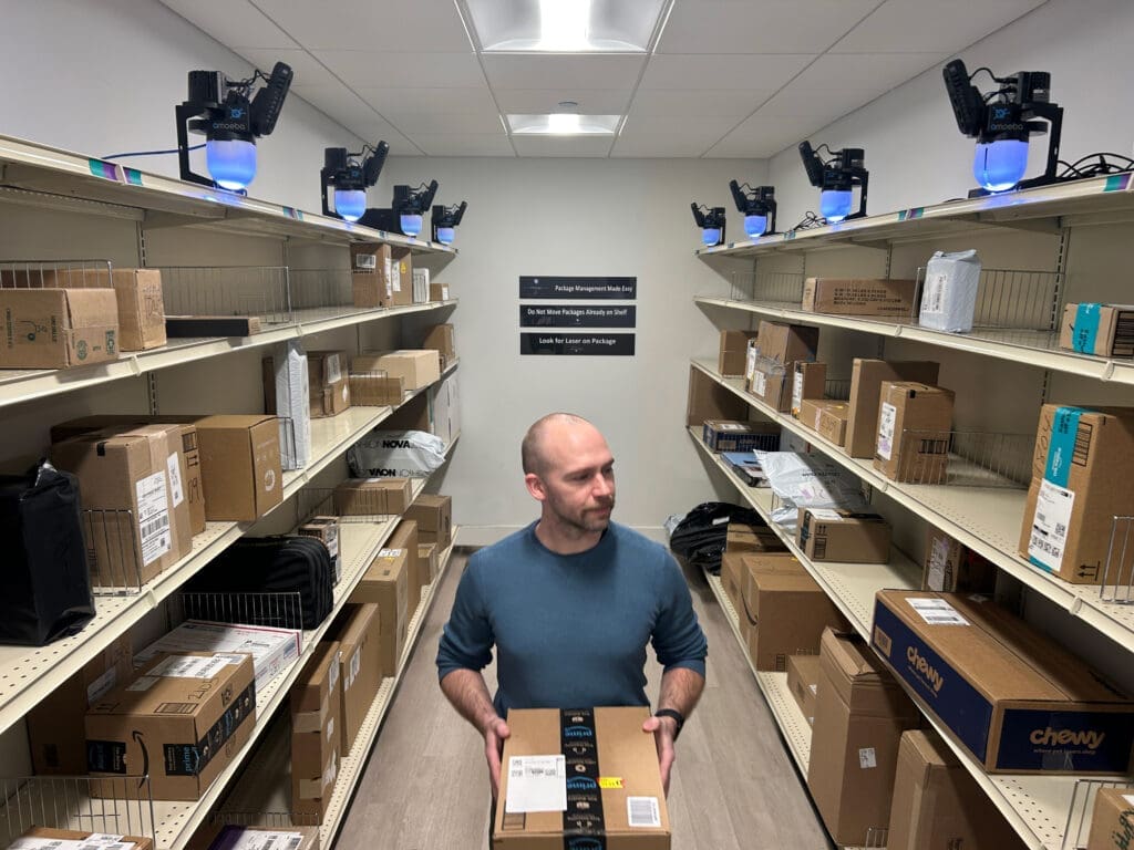 Resident retrieving parcels from an AI-enabled Smart Package Room with open shelving and precision-tracking modules, demonstrating how to automate package management in multifamily buildings efficiently and securely. 